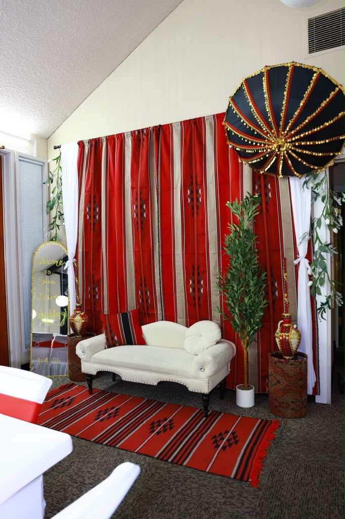 A traditional lounge corner with red woven drapes, a cream sofa and olive trees